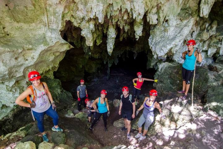 A group of tourists pose for a photo at the mouth of a cave in Puerto Rico